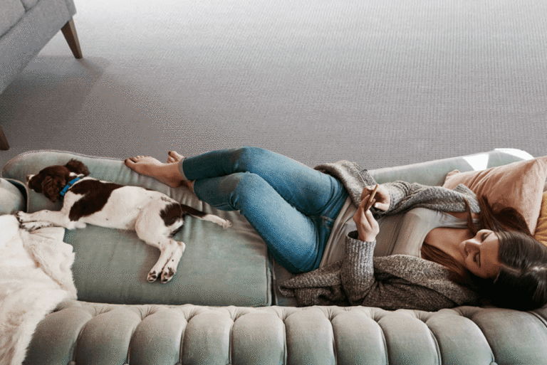 Woman relaxing at home with a dog on a sofa.