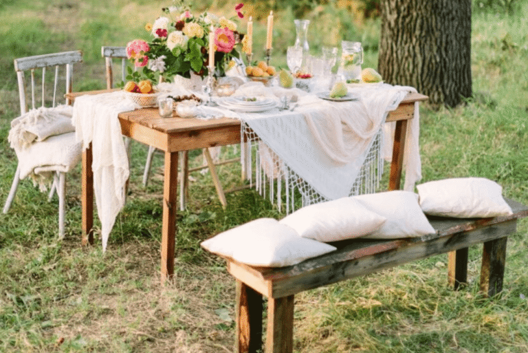 Outdoor dining table styled for summer entertaining with flowers and soft furnishings.