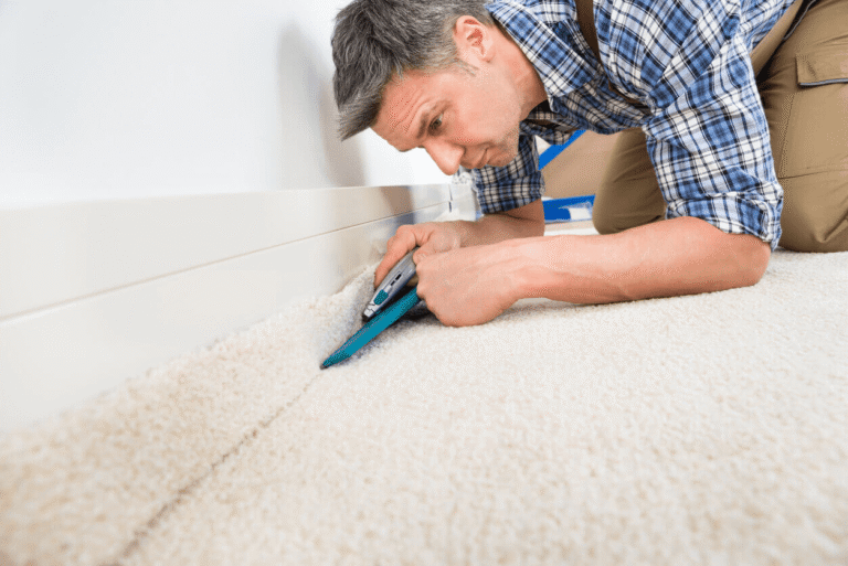 Installer cutting and fitting carpet along a wall during a flooring installation