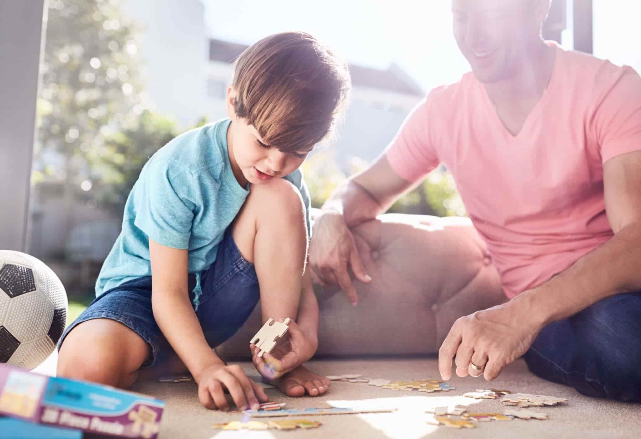 A father and son playing jigsaw puzzles on a carpeted floor
