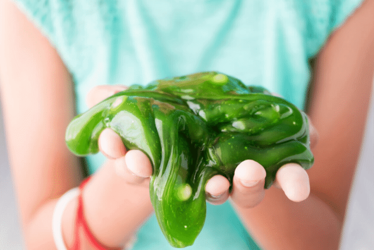 Child holding green slime in their hands.