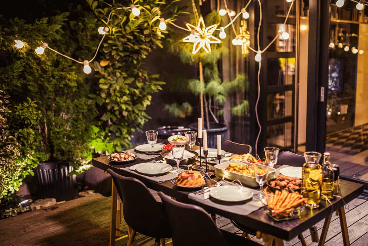 Outdoor dining table set for an evening gathering with string lights.