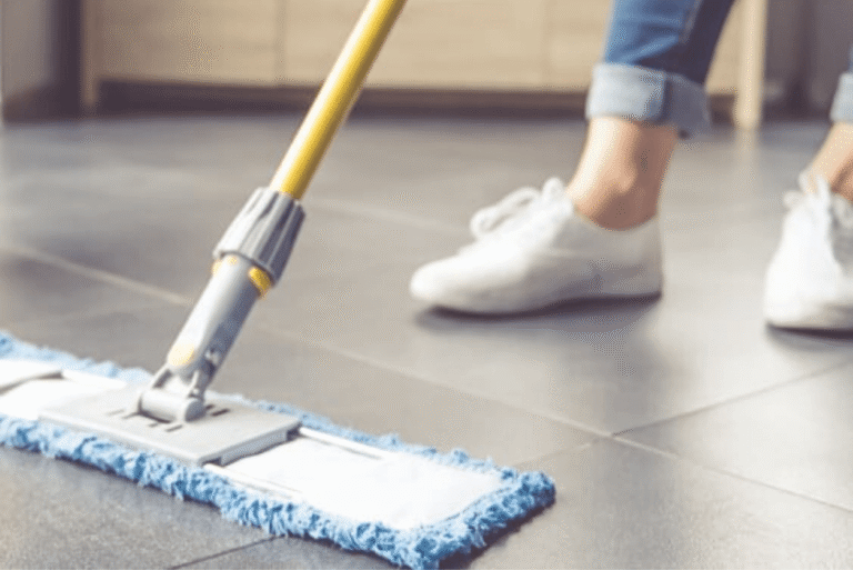 Person mopping tiled floor with a flat mop during routine cleaning