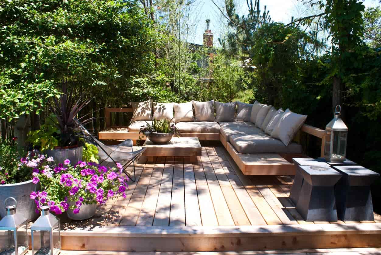 Timber deck with outdoor lounge seating surrounded by lush garden greenery.