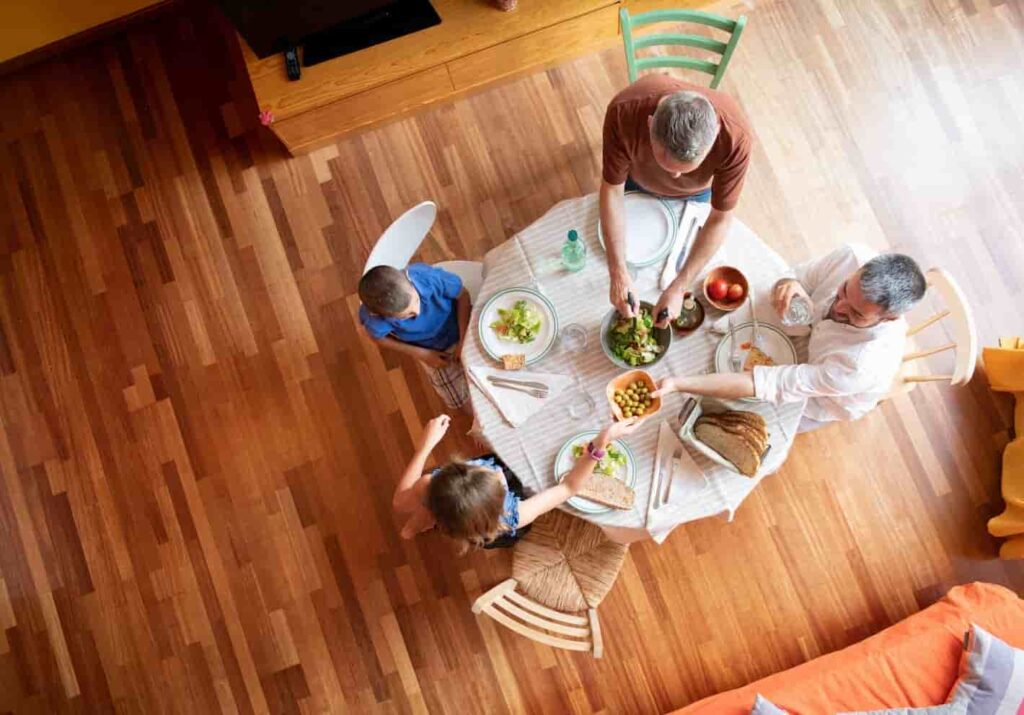 Top-down view of family eating at table on timber-finish flooring in a bright living space