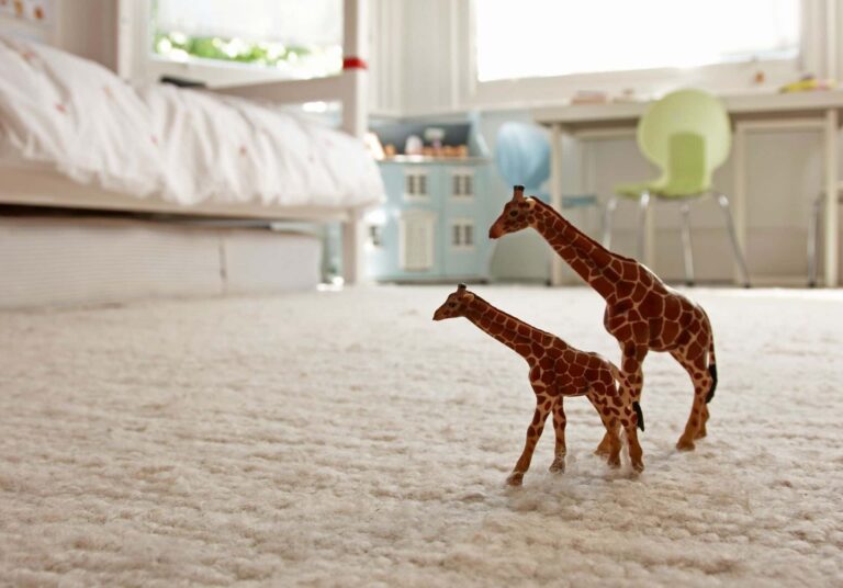 Children’s bedroom with wool carpet and toy giraffes on the floor.