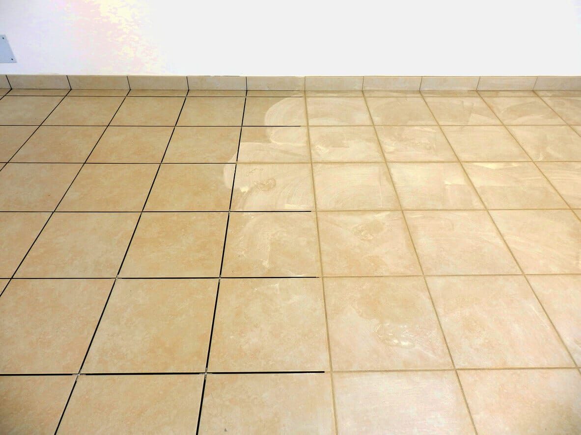 Tiled floor showing adhesive or grout residue on one section,