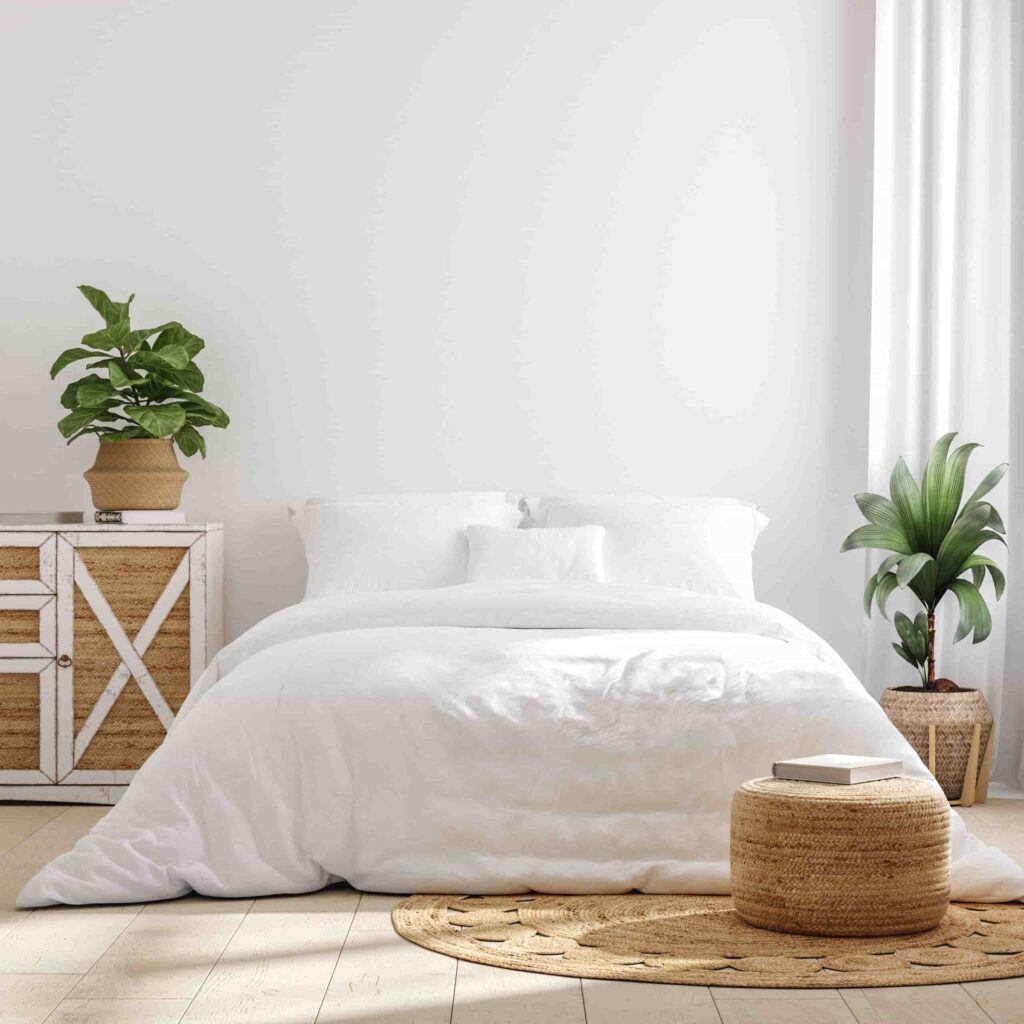 Bedroom featuring white bedding, light flooring, woven furniture, and indoor plants.