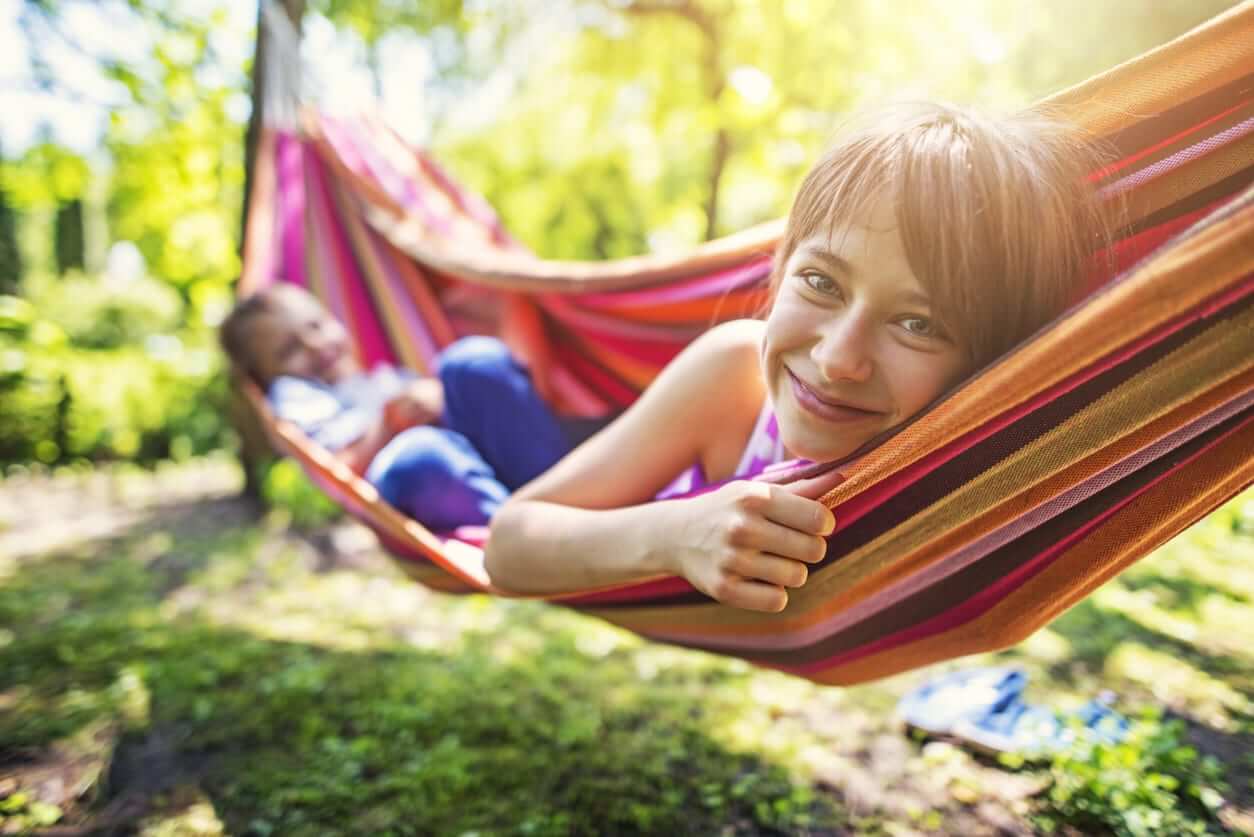 Children relaxing in a colourful hammock in a leafy backyard, enjoying a comfortable outdoor space designed for family downtime.