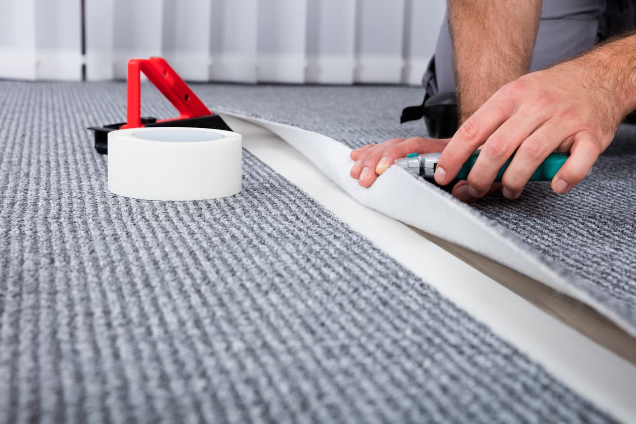 Professional installer fitting carpet using specialist tools