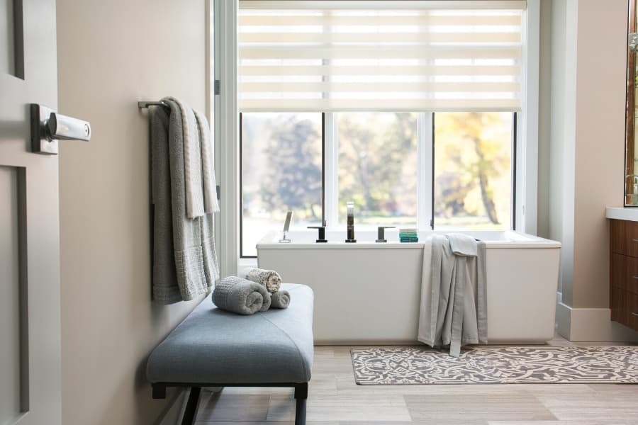 A bathroom interior featuring a window with roller shades.
