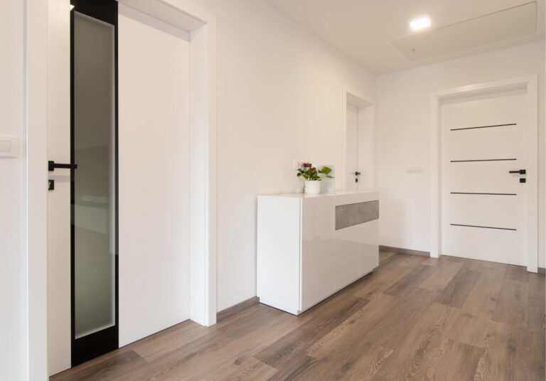 Hallway with white walls, modern doors, and laminate flooring.