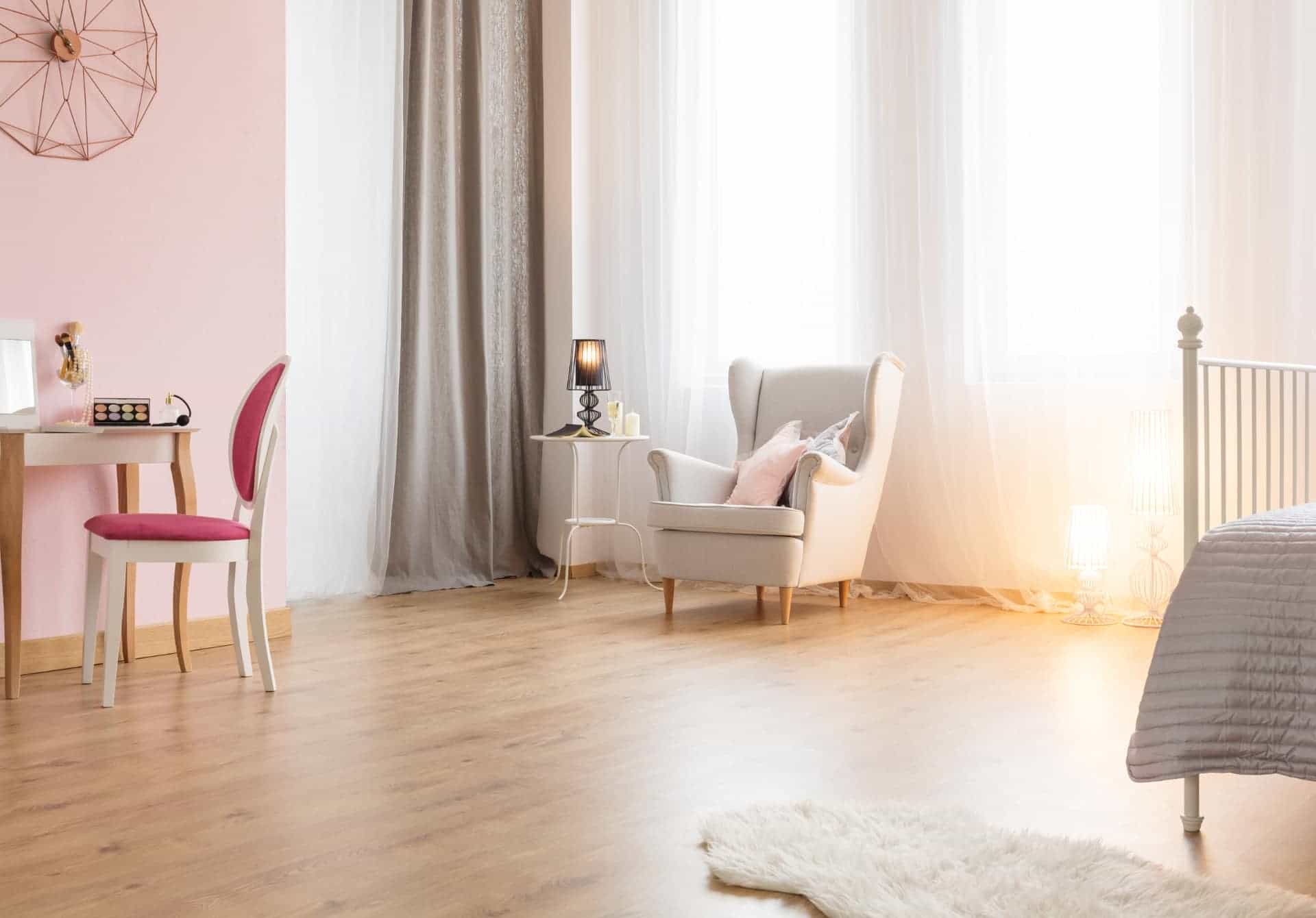 A bedroom with flowing curtains featuring laminate as flooring