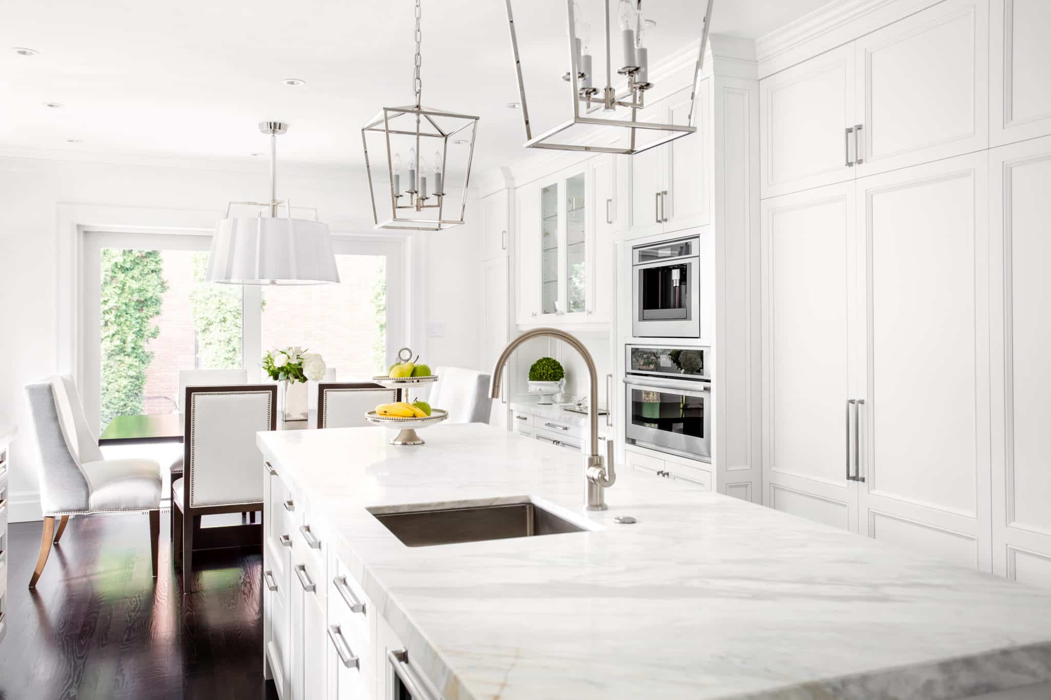 Elegant white kitchen with dark timber flooring and marble island benchtop