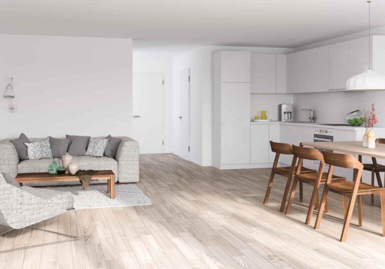 An open concept living, dining and kitchen space with white walls and light-coloured flooring.