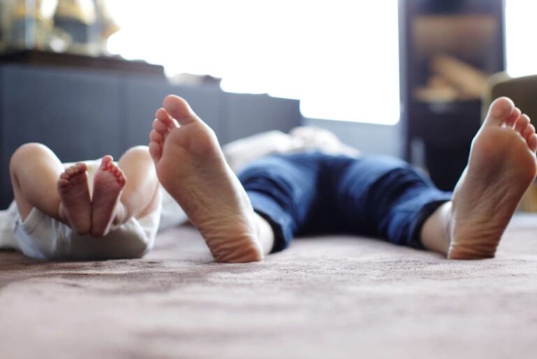 A child and adult lying on a carpeted floor