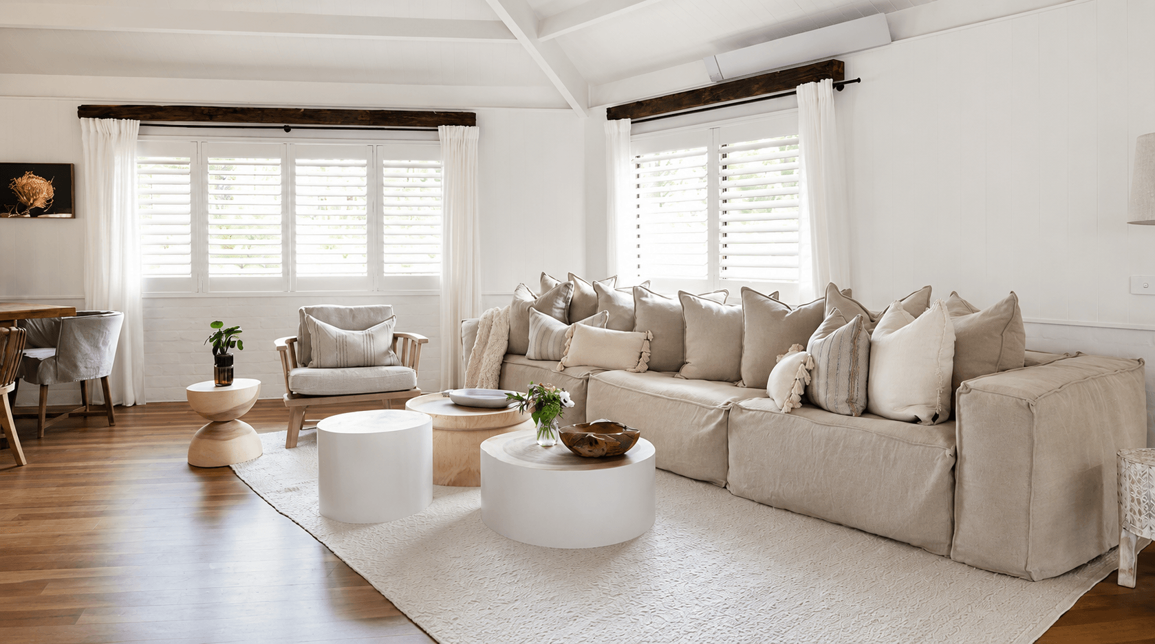 Bright modern farmhouse living room with white shutters, neutral furniture and timber look flooring