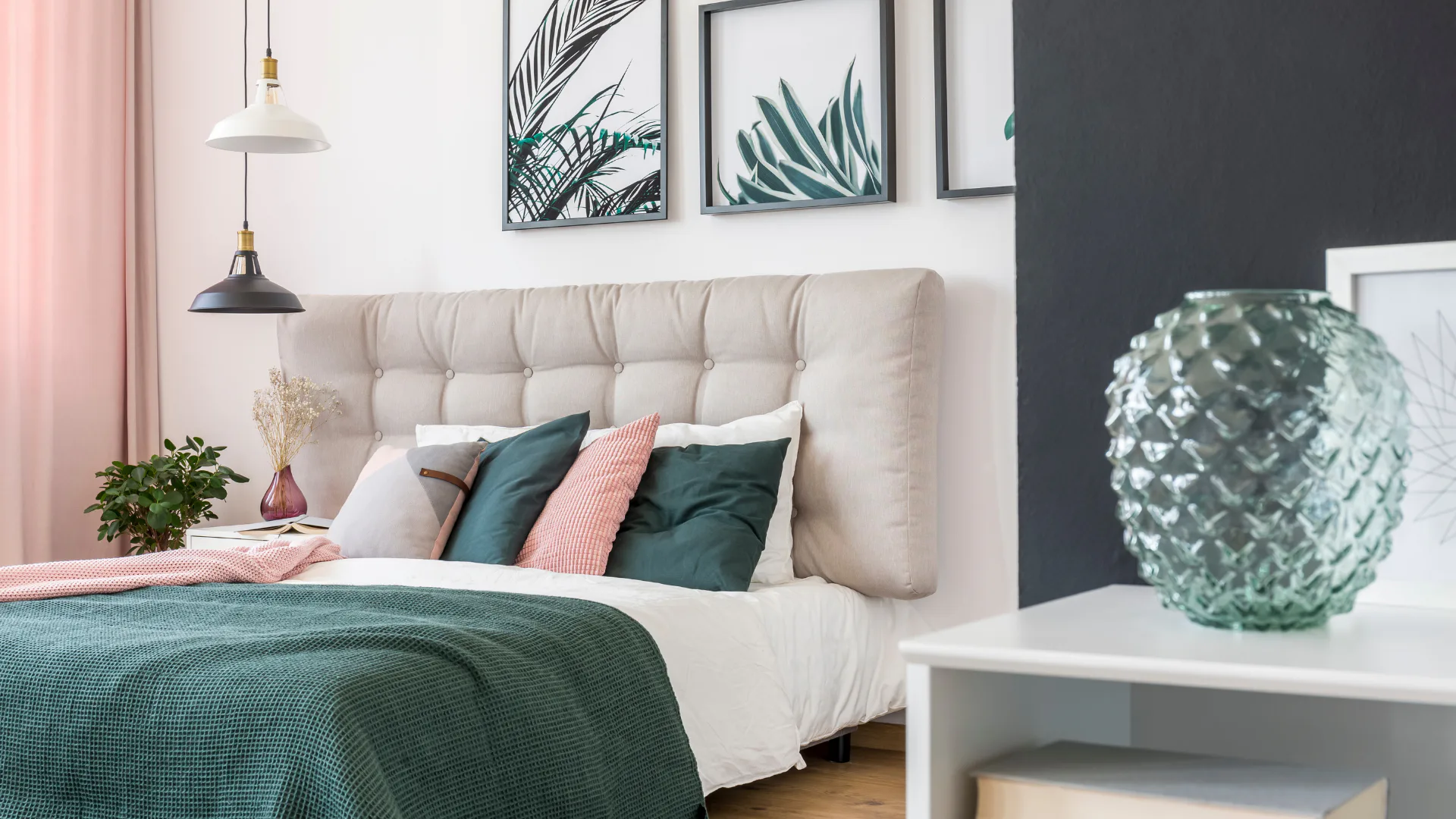 Contemporary bedroom featuring a cream tufted headboard, teal and pink throw pillows, botanical wall art prints, pendant lighting, pink curtains, potted plants, and a textured green decorative sphe...