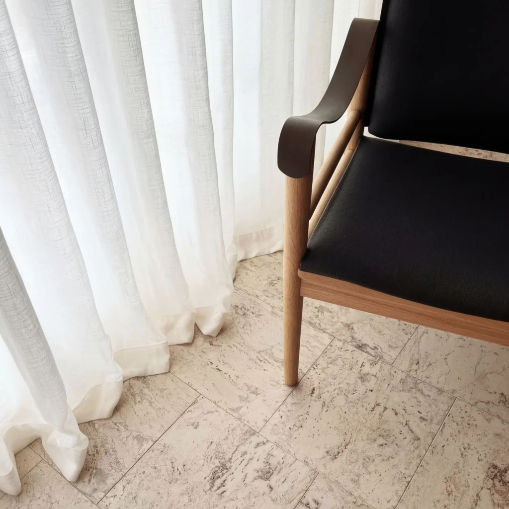 Natural cork flooring with textured surface pattern, paired with white sheer curtains and a modern wooden chair with black upholstery in a contemporary interior space.