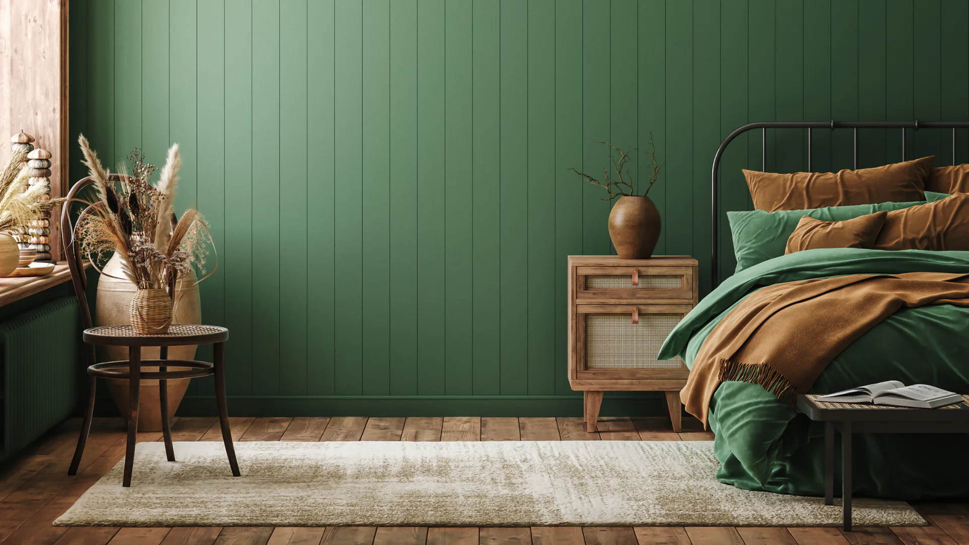 Contemporary bedroom featuring sage green paneled accent wall, metal bed frame with layered brown and green bedding, wooden nightstand with ceramic vase, and dried pampas grass arrangement on round...