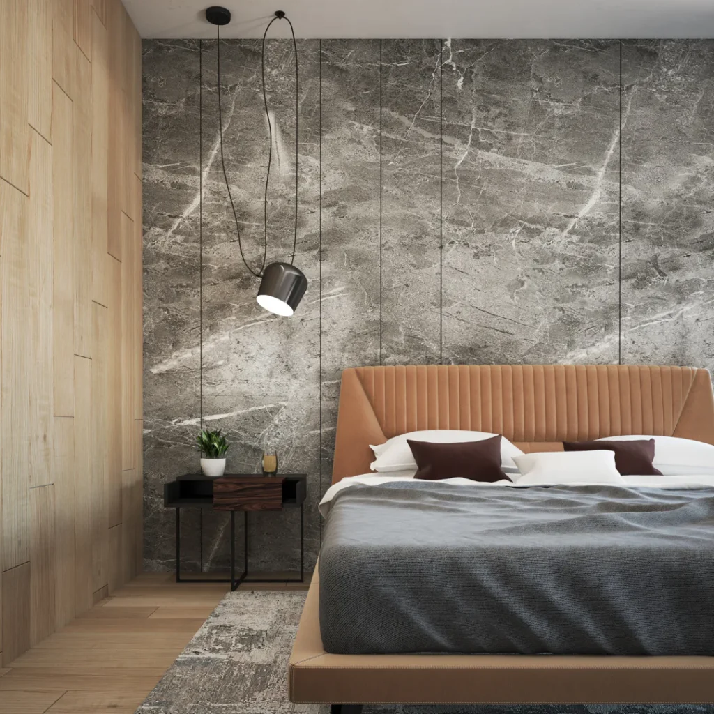 Contemporary bedroom featuring a tan leather headboard, gray bedding, dark marble accent wall with vertical paneling, wooden nightstand with potted plant, and black cylindrical pendant light.