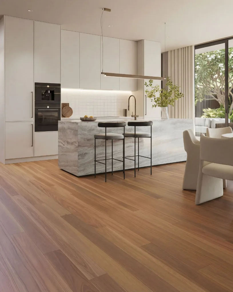 Contemporary open-plan kitchen featuring warm honey-toned engineered timber flooring, white minimalist cabinetry, marble waterfall island with black bar stools, and large windows overlooking garden