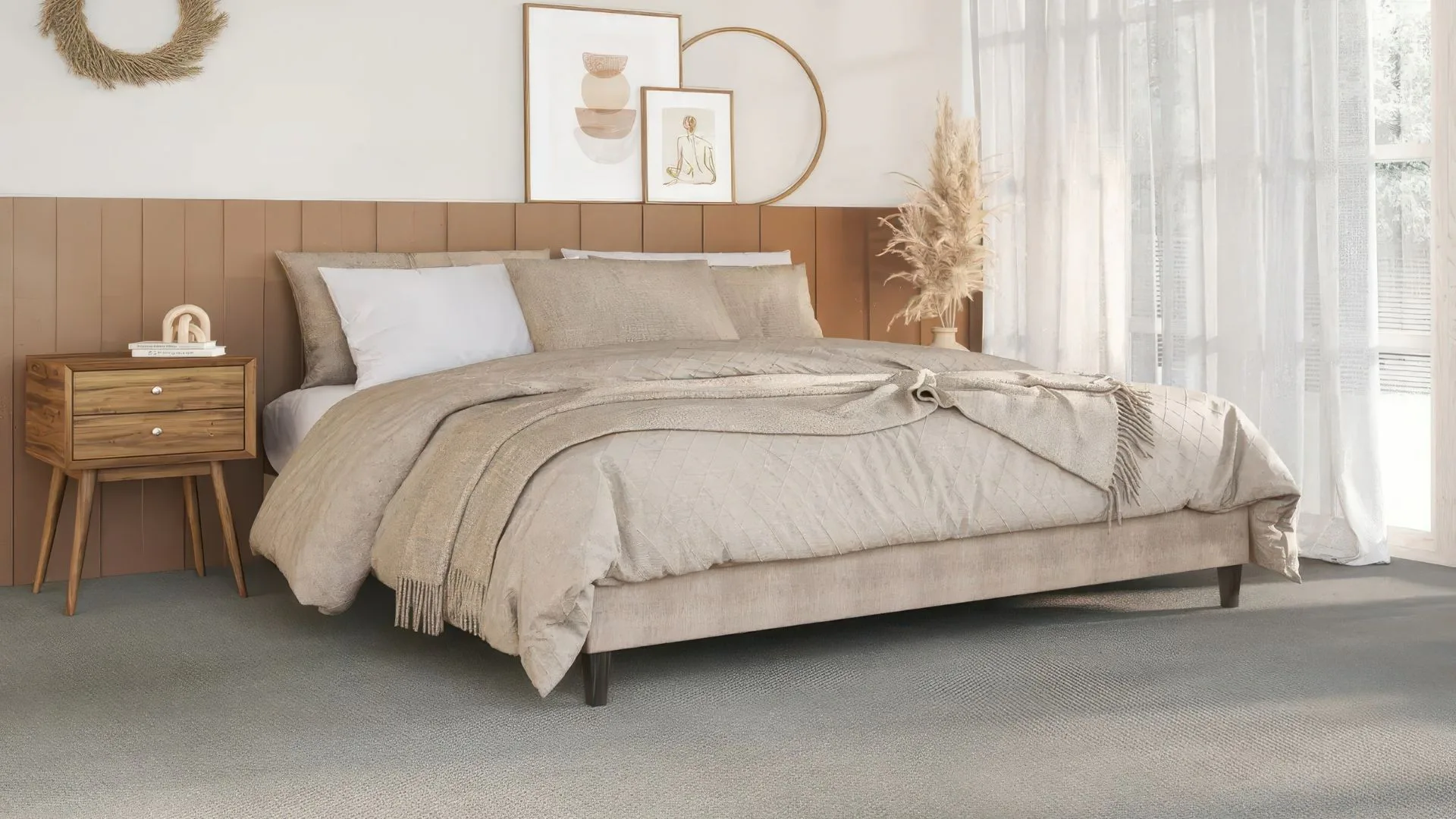 Spacious bedroom featuring a beige upholstered bed with neutral bedding, wooden nightstand, and framed wall art above a tan padded headboard, showcasing soft comfortable carpet flooring.