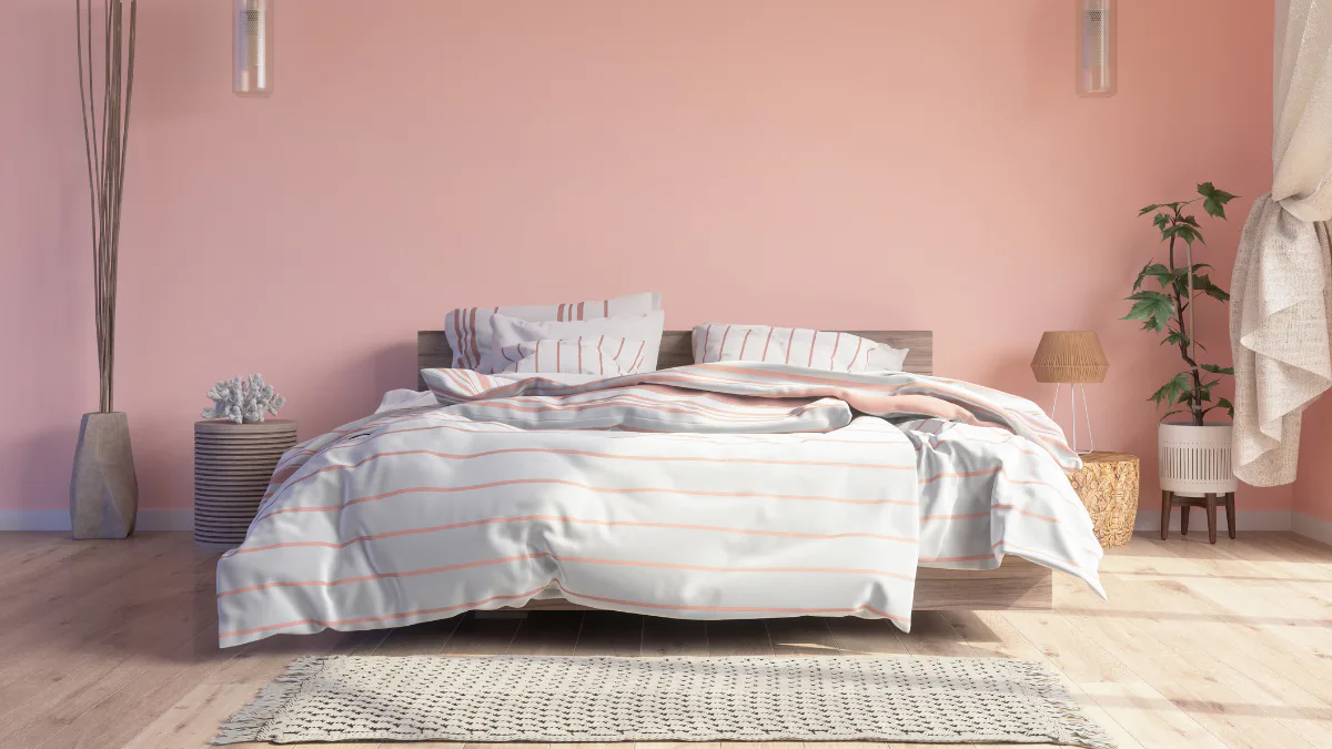Contemporary bedroom featuring a bed with striped white and coral bedding, dark wood headboard, pink painted walls, wooden nightstands, potted plant, textured area rug, pendant lights, and natural ...