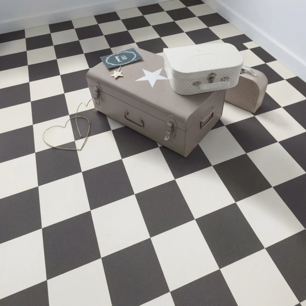 Vintage suitcases and decorative boxes arranged on a black and white checkered sheet vinyl floor, displaying classic retro flooring pattern and texture