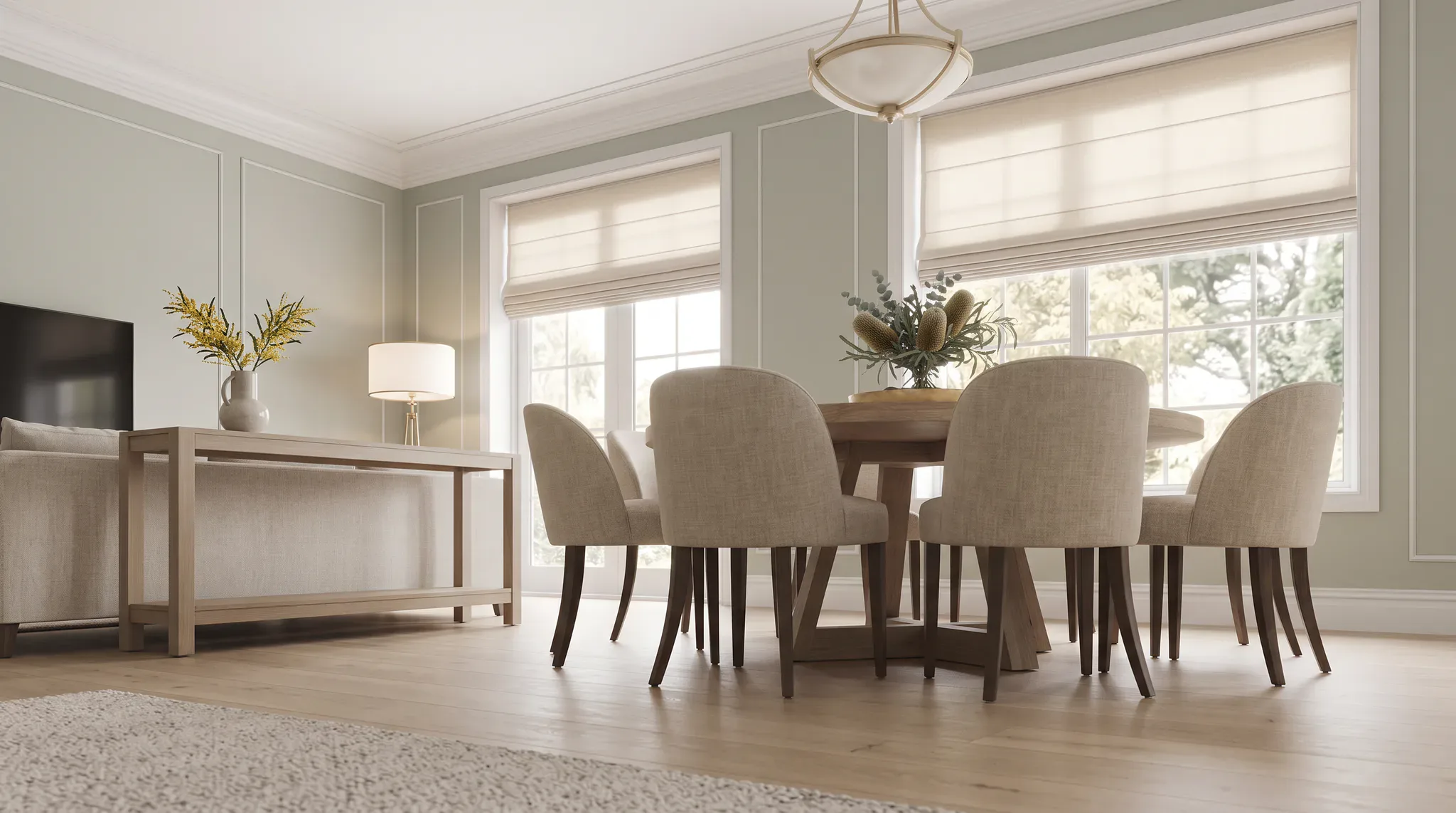 Bright transitional dining room featuring a round wooden table with four upholstered beige chairs, large windows with roman blinds, hardwood flooring, area rug, pendant lighting, and minimalist wal...